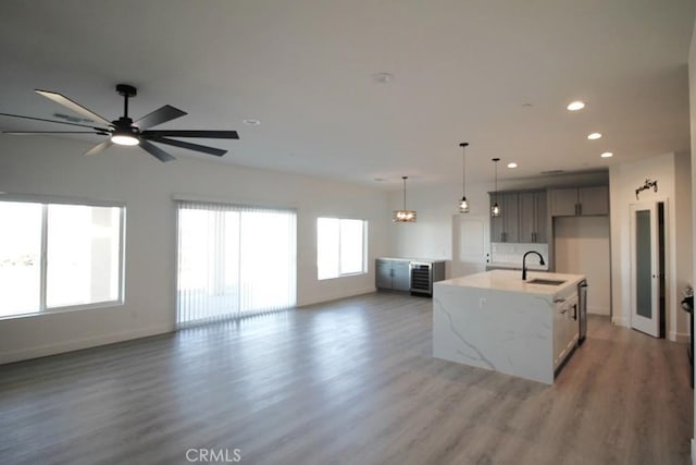 kitchen featuring sink, an island with sink, a wealth of natural light, and dark wood-type flooring