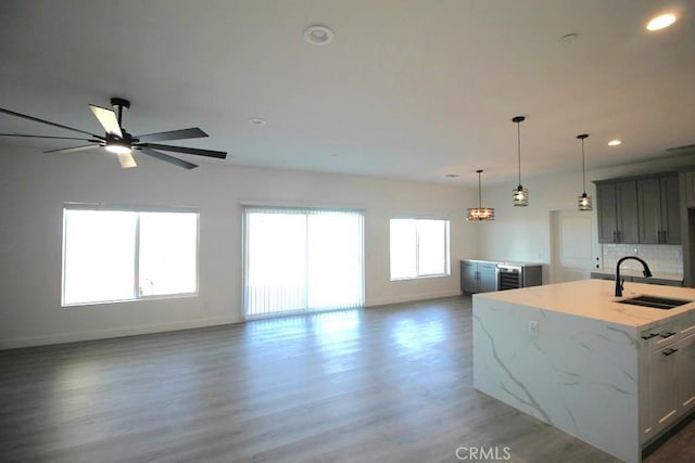 kitchen featuring dark hardwood / wood-style flooring, light stone countertops, sink, and an island with sink