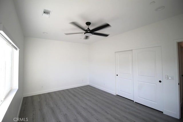 unfurnished bedroom with a closet, dark hardwood / wood-style floors, and ceiling fan