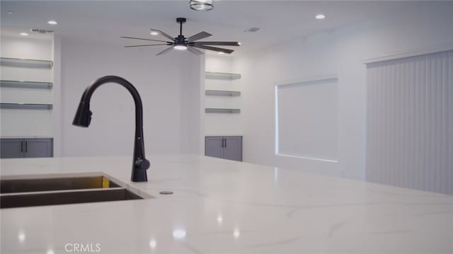 details with ceiling fan, light stone countertops, and sink