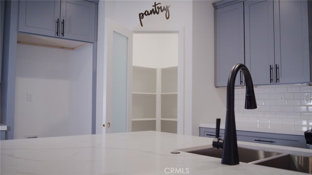 kitchen with decorative backsplash, light stone counters, and sink