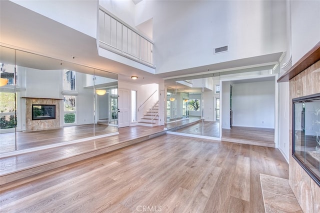 unfurnished living room with a high ceiling, a fireplace, and light hardwood / wood-style floors