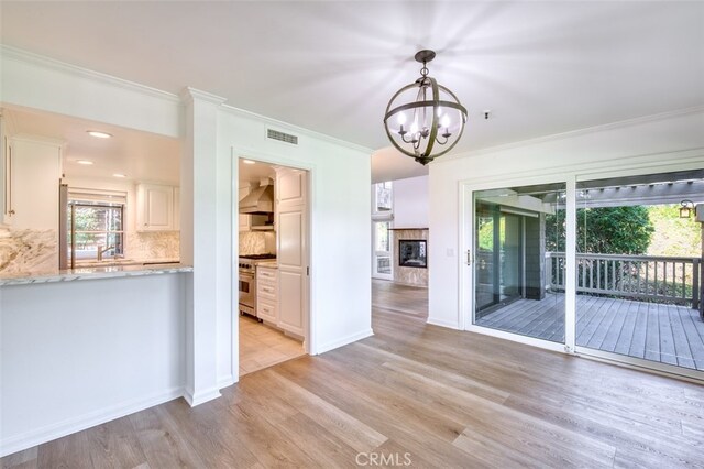 interior space featuring crown molding, light hardwood / wood-style flooring, and a notable chandelier