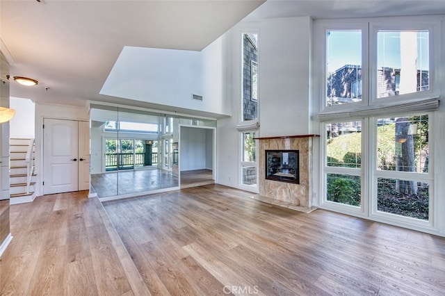 unfurnished living room with a premium fireplace, a wealth of natural light, and light wood-type flooring