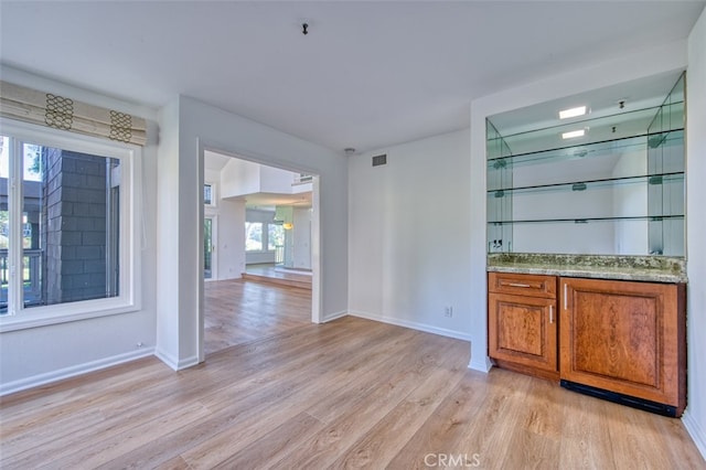 bar with light hardwood / wood-style floors and light stone counters