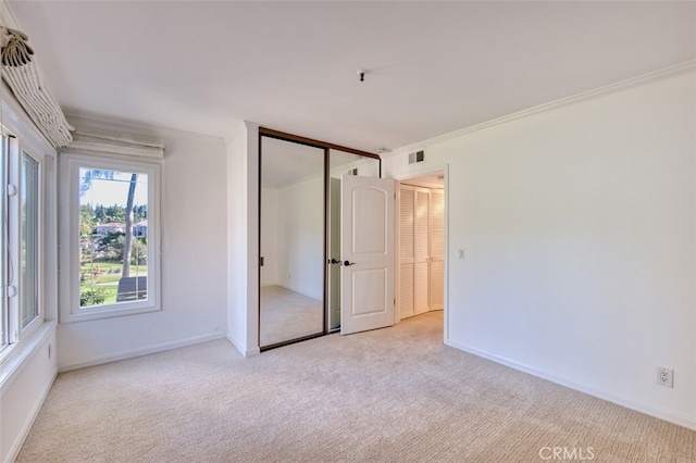 unfurnished bedroom with crown molding, light colored carpet, and a closet