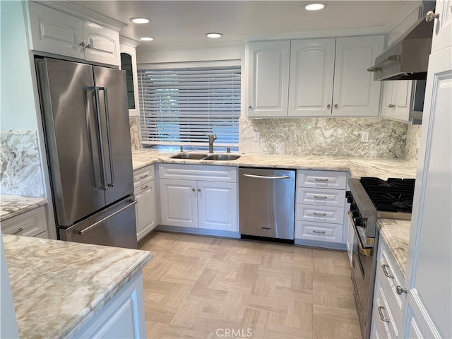 kitchen with light stone countertops, sink, high quality appliances, white cabinetry, and exhaust hood