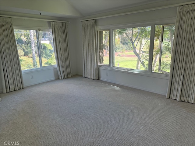 empty room featuring vaulted ceiling, light carpet, and plenty of natural light