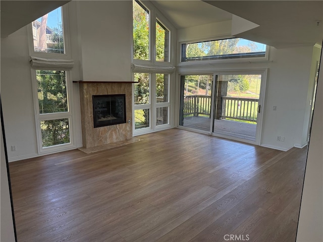 unfurnished living room featuring a premium fireplace, wood-type flooring, and a healthy amount of sunlight