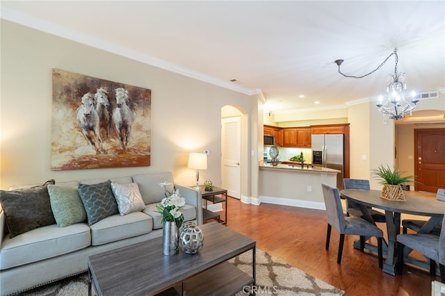 living room featuring a notable chandelier, ornamental molding, and dark hardwood / wood-style floors