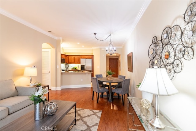 living room featuring sink, dark wood-type flooring, a notable chandelier, and crown molding