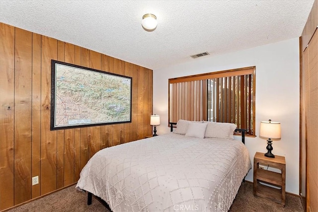 bedroom with wood walls, a closet, dark carpet, and a textured ceiling