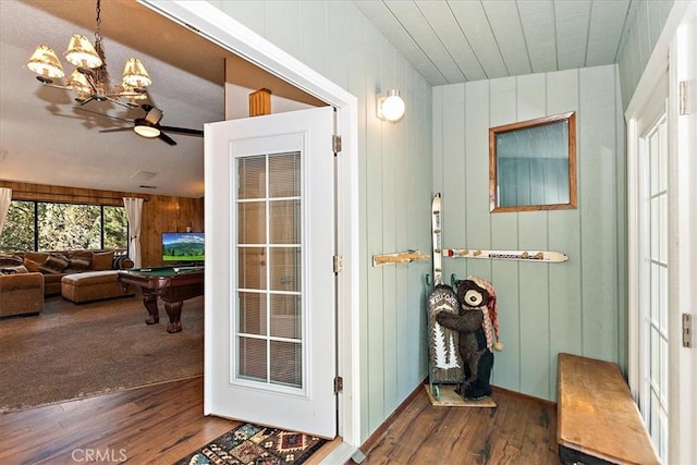 doorway to outside featuring ceiling fan with notable chandelier, dark hardwood / wood-style floors, pool table, and wood walls