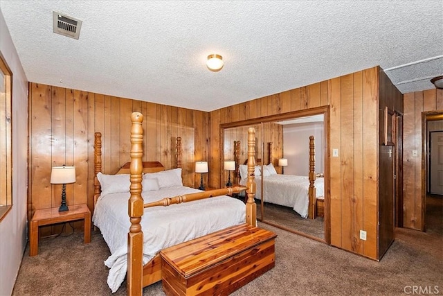 carpeted bedroom featuring a textured ceiling, a closet, and wood walls