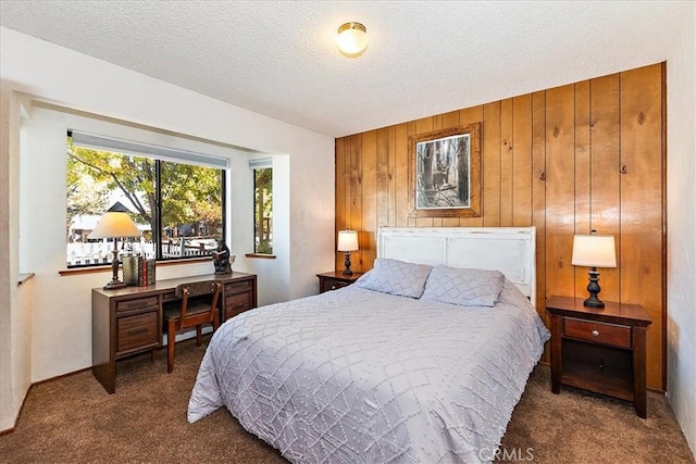 carpeted bedroom with a textured ceiling and wood walls