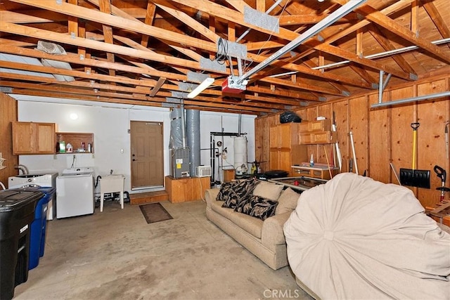 garage featuring washing machine and dryer, wooden walls, heating unit, and gas water heater