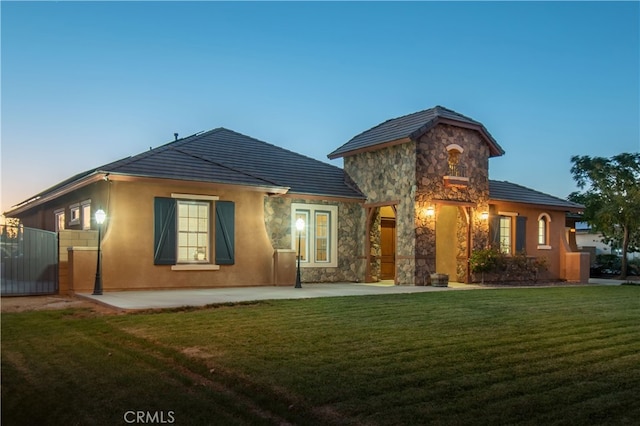 view of front of home with a patio area and a yard