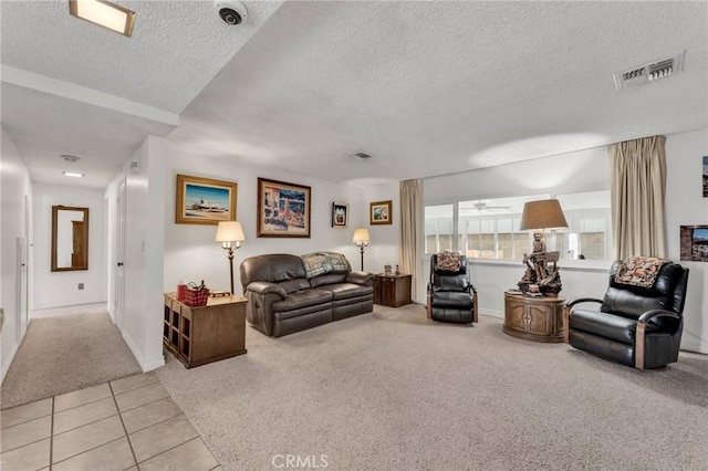 living room with ceiling fan, light colored carpet, and a textured ceiling