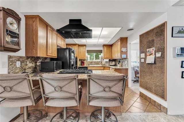 kitchen with extractor fan, kitchen peninsula, a kitchen bar, decorative backsplash, and black appliances