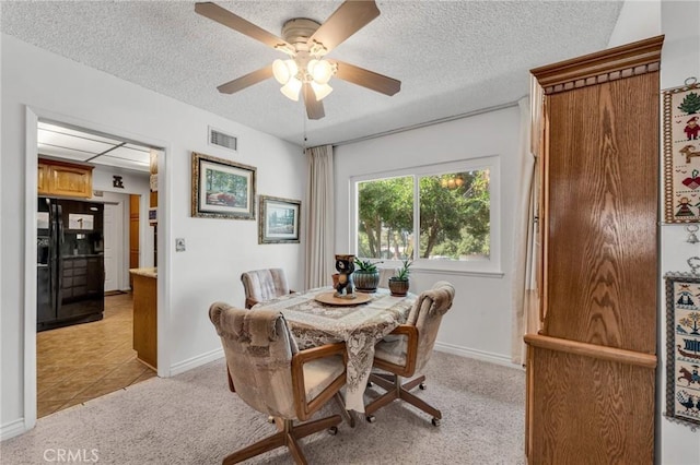 dining space with ceiling fan, light carpet, and a textured ceiling