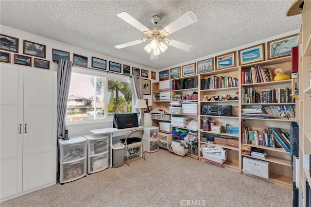 carpeted home office featuring ceiling fan and a textured ceiling