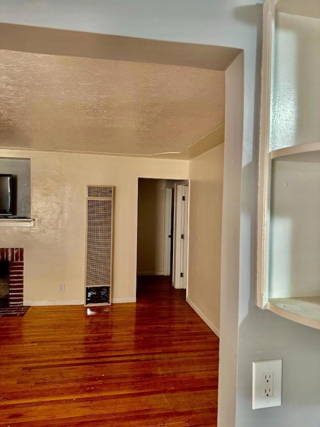 unfurnished living room with a textured ceiling, dark wood-type flooring, and a fireplace