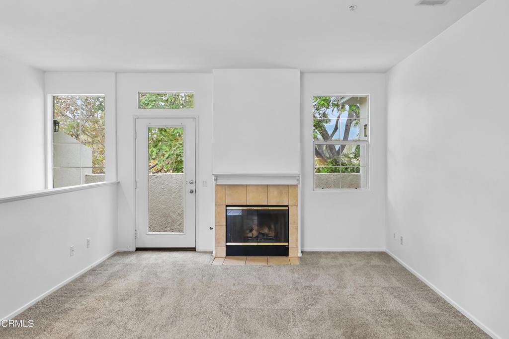 unfurnished living room with light colored carpet and a tile fireplace