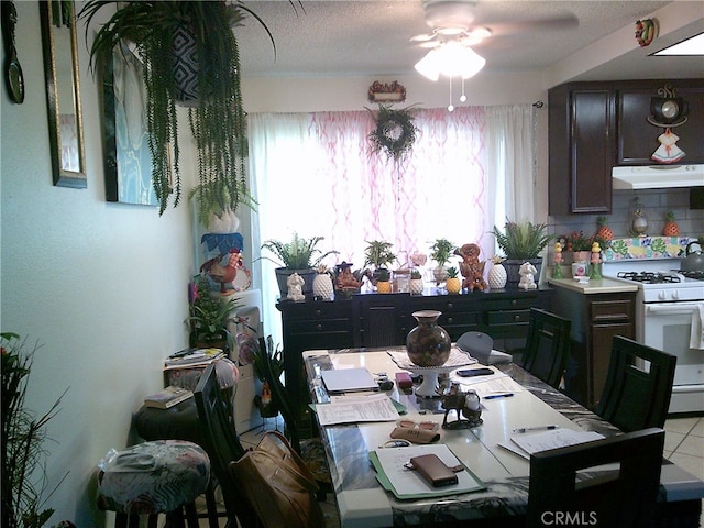 tiled dining space featuring a textured ceiling and ceiling fan