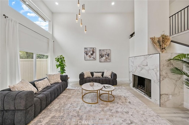 living room featuring a premium fireplace, a towering ceiling, and light hardwood / wood-style floors