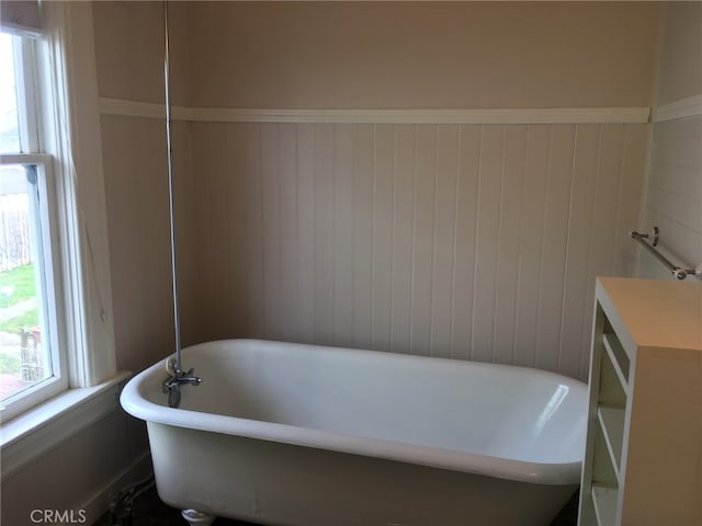 bathroom featuring a bathtub and wood walls