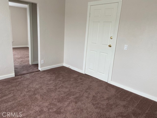 unfurnished room with dark colored carpet