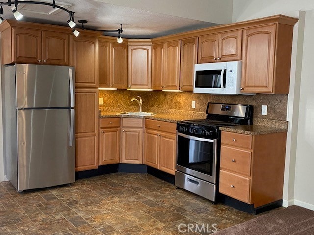 kitchen with tasteful backsplash, stainless steel appliances, sink, and light stone counters