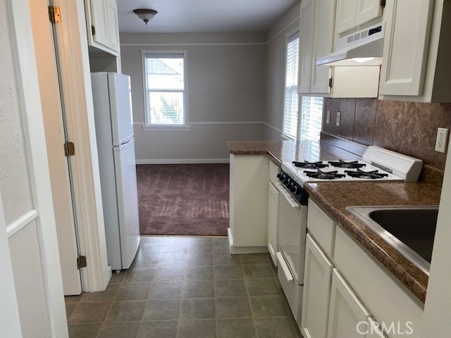 kitchen with white cabinets, dark carpet, backsplash, and white appliances