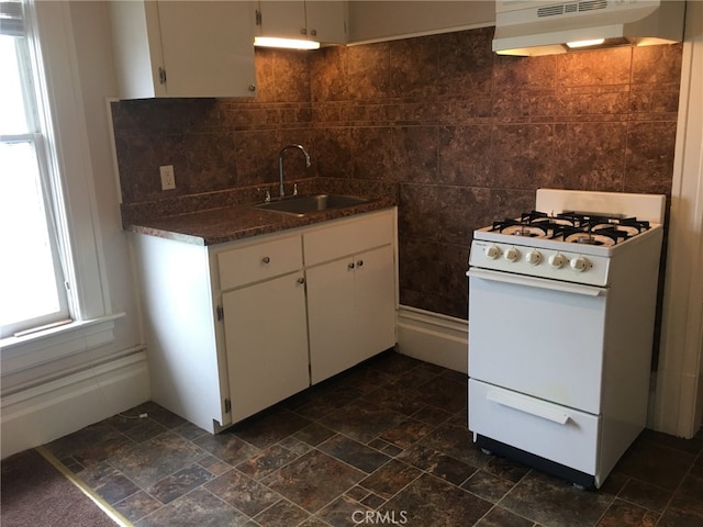 kitchen with tasteful backsplash, white gas range, white cabinetry, sink, and ventilation hood