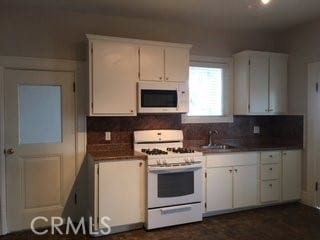 kitchen with white appliances, decorative backsplash, and white cabinets