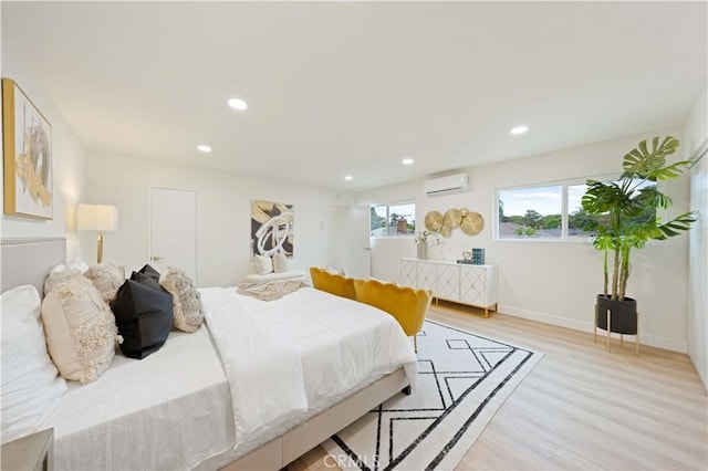 bedroom with a wall mounted AC and light hardwood / wood-style floors