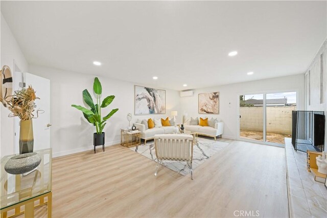 living room with light hardwood / wood-style floors and an AC wall unit