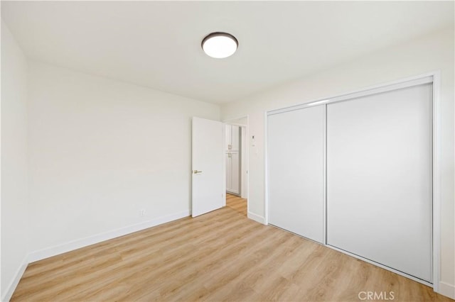 unfurnished bedroom with a closet and light hardwood / wood-style flooring