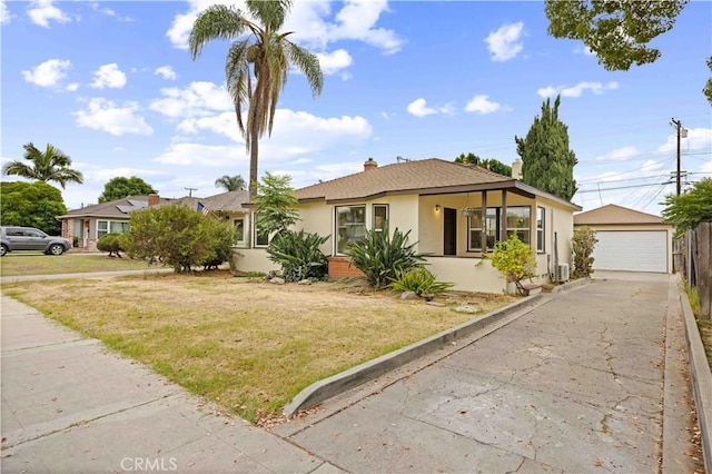 view of front of property featuring a front yard, stucco siding, a detached garage, and an outbuilding