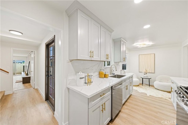 kitchen with light stone countertops, backsplash, stainless steel appliances, sink, and light hardwood / wood-style flooring