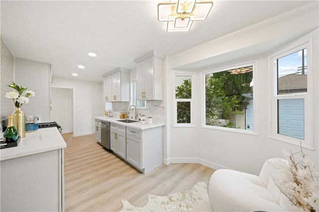 kitchen with white cabinetry, dishwasher, sink, decorative backsplash, and light wood-type flooring