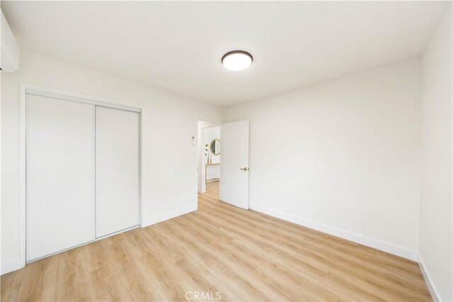 unfurnished bedroom with light wood-type flooring and a closet