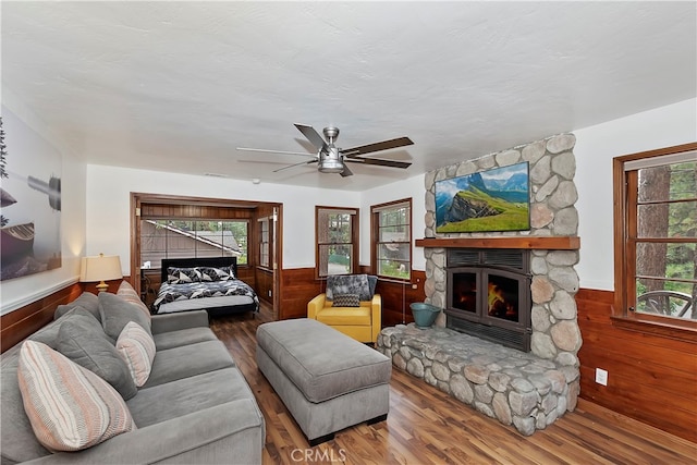 living room featuring ceiling fan, a fireplace, hardwood / wood-style flooring, and wood walls