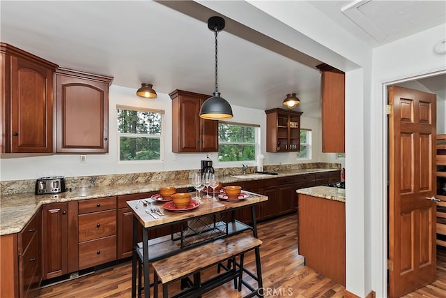 kitchen featuring dark hardwood / wood-style floors, decorative light fixtures, sink, and light stone counters