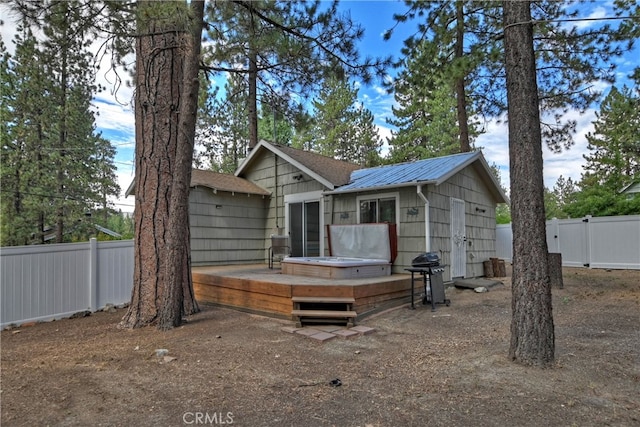 rear view of house featuring a deck and a jacuzzi