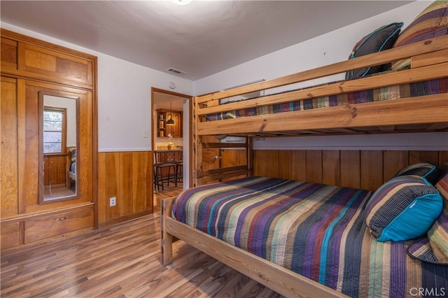 bedroom with hardwood / wood-style floors and wood walls