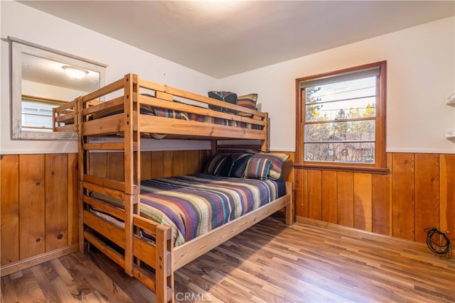 bedroom with hardwood / wood-style flooring and wooden walls