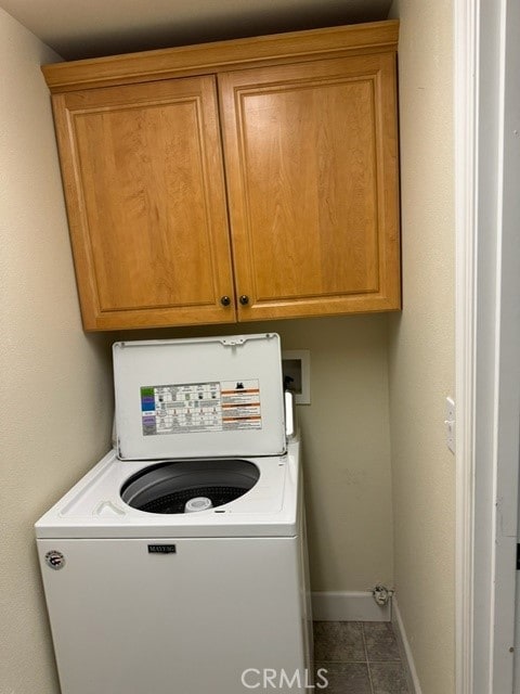 clothes washing area with washer / clothes dryer, tile patterned flooring, and cabinets