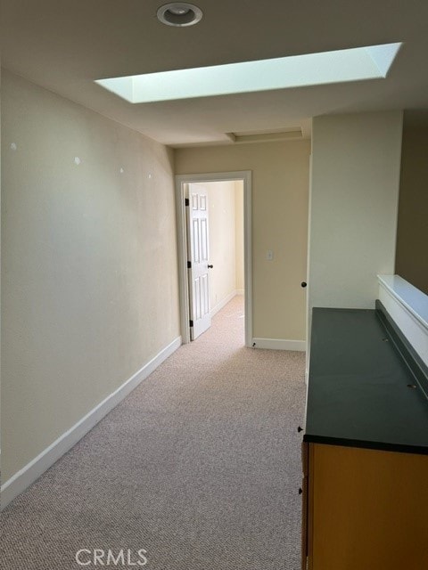 hallway featuring a skylight and light carpet