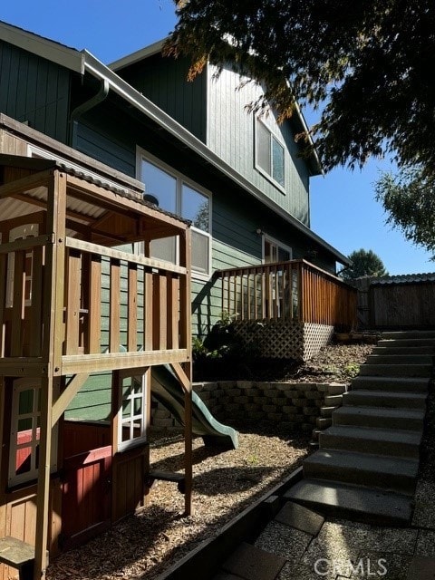 view of property exterior with a playground and a wooden deck